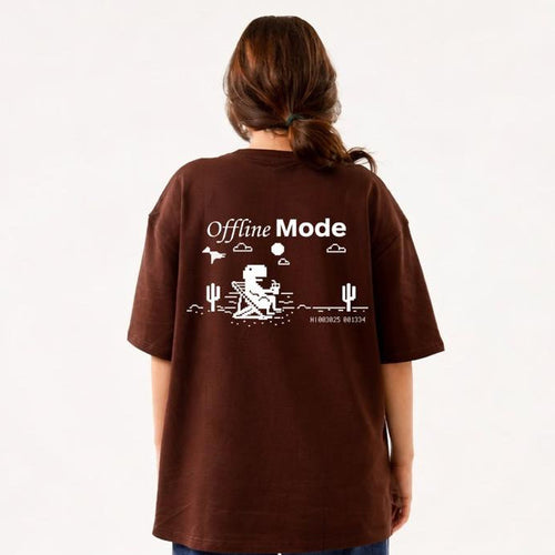 Person wearing a brown t-shirt with 'Offline Mode' text and graphics on the back, standing against a white background.